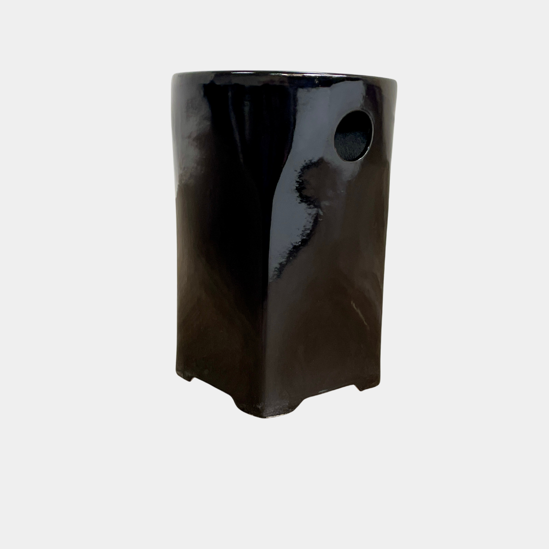 Discover the elegance of the Artelano Tian Di Ceramic Stool, crafted by Artelano using modern techniques. This glossy black stool features a square shape with rounded edges and a circular cutout near the top, combining functionality with style.