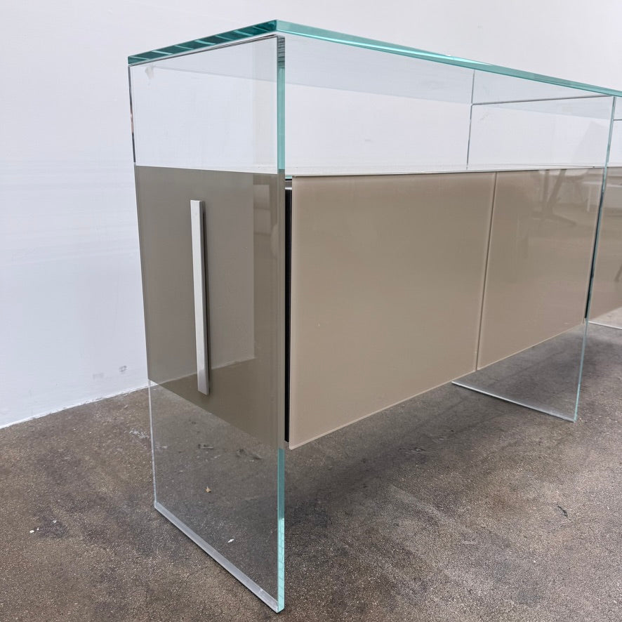 A long Gallotti & Radice Air Console Table featuring a clear glass frame and four opaque taupe storage cabinets.