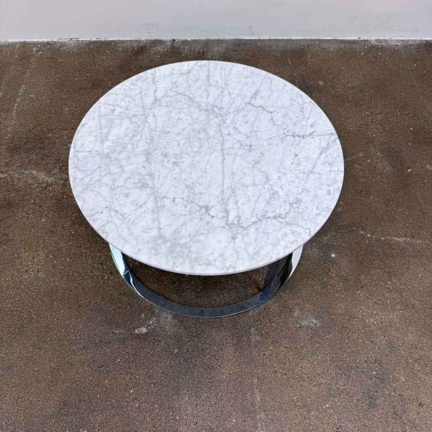B&B Italia Mera Round Coffee Table with a white Carrara marble top and a dark metal circular base.