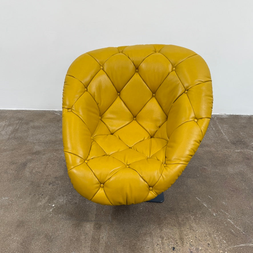 The Moroso Bohemian Low Armchair by Moroso features mustard yellow tufted leather upholstery, a matching cushion, and a black metal pedestal base, shown against a plain white background.