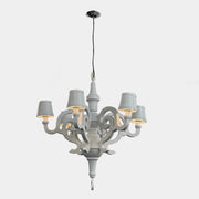 A white Moooi Paper Chandelier by Modern Resale with six arms and lampshades hangs from the ceiling on a black cord, serving as a striking 6 Light Chandelier centerpiece against a plain background.