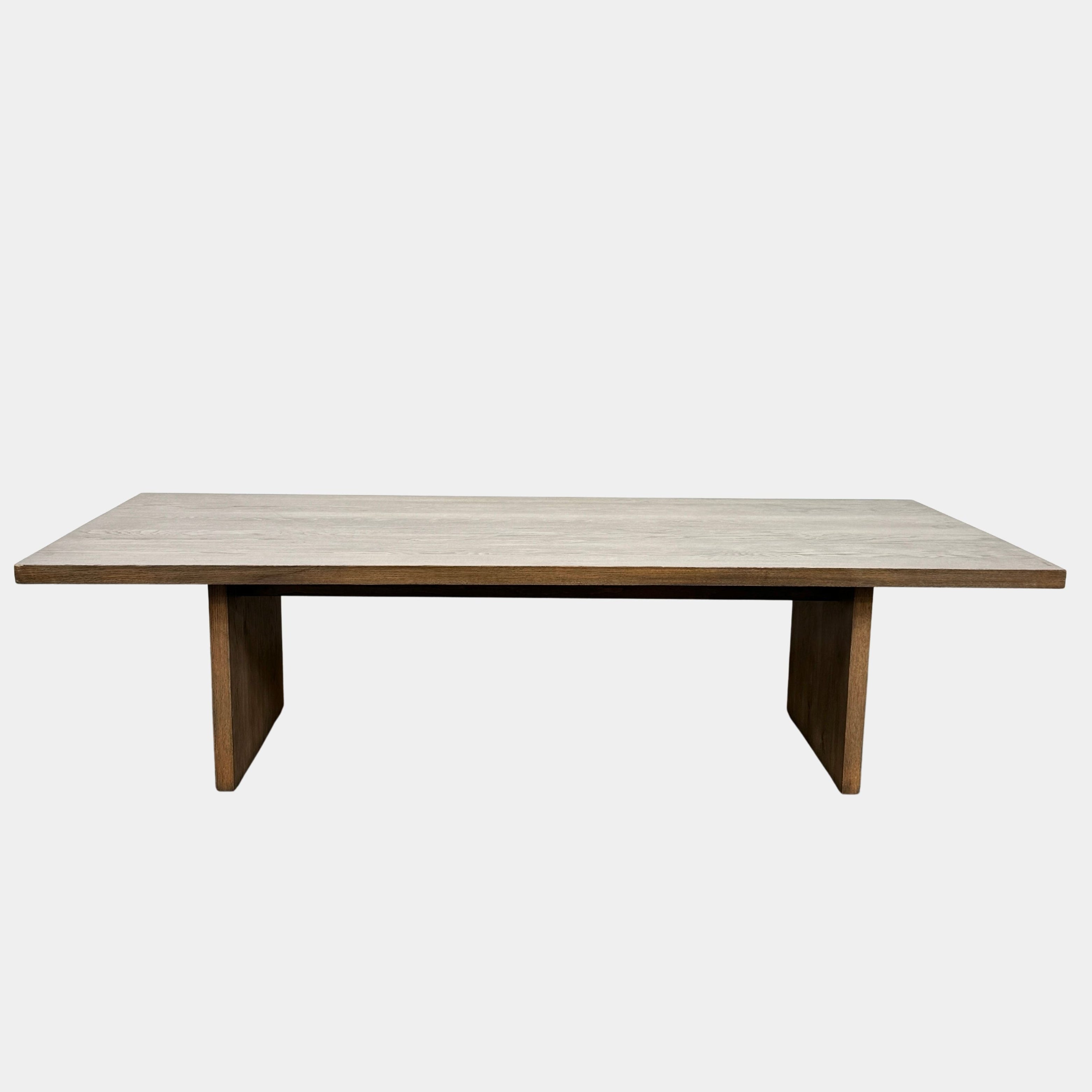 A close-up of the BDDW Solid Oak dining table by Modern Resale, showcasing its wooden surface with visible grain patterns and a grayish-brown finish.