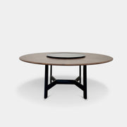 Round wooden table with a central raised circular platform and sleek black legs, reminiscent of the elegant design seen in the B&B Italia Alex Dining Table With Rotating Marble Tray. The rotating marble tray adds a refined touch, making it a versatile centerpiece on a white background.