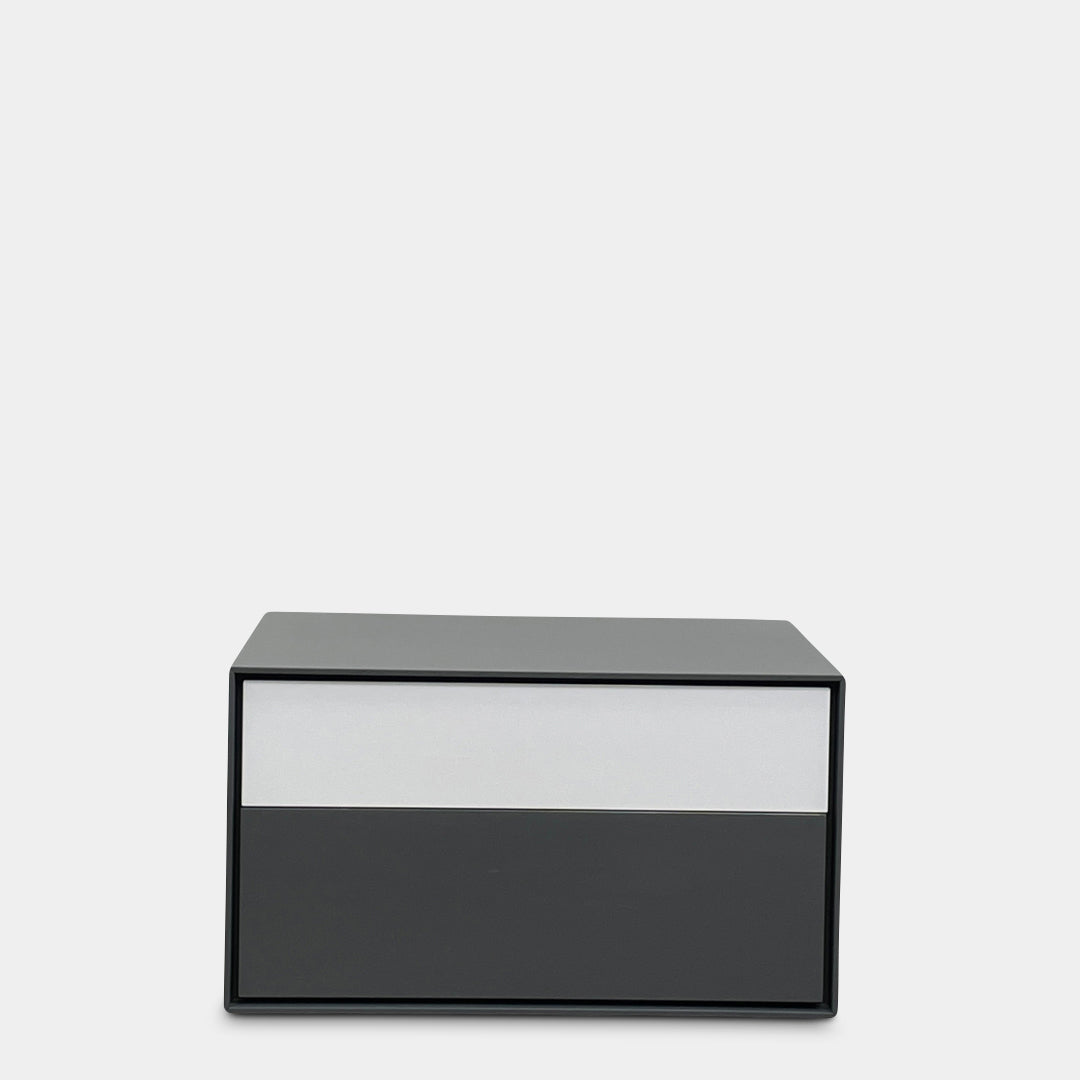 A rectangular gray and white lacquer box from B&B Italia, reminiscent of the Dado Night Table's minimalist design, features a glossy upper and matte lower section. This sleek piece serves as a stylish bedside companion, enhancing any modern space against a plain white background.