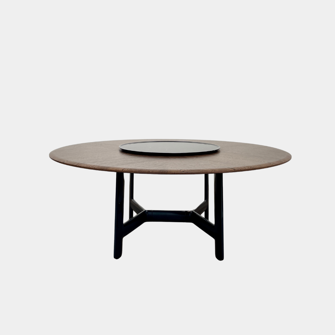 Round wooden table with a central raised circular platform and sleek black legs, reminiscent of the elegant design seen in the B&B Italia Alex Dining Table With Rotating Marble Tray. The rotating marble tray adds a refined touch, making it a versatile centerpiece on a white background.