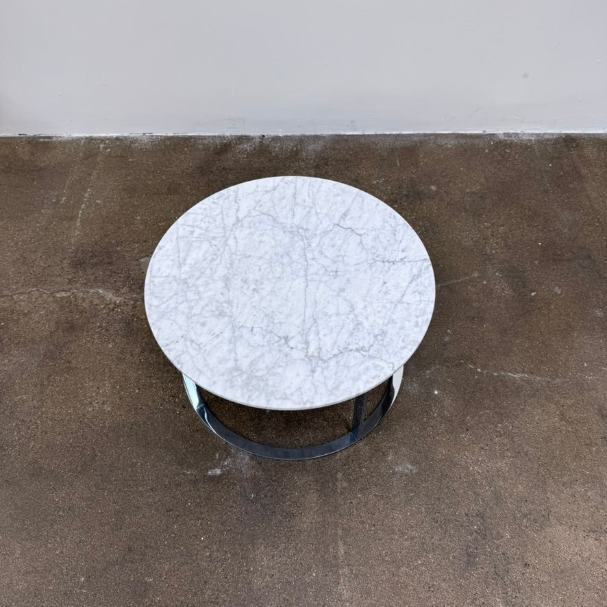B&B Italia Mera Round Coffee Table with a white Carrara marble top and a dark metal circular base.