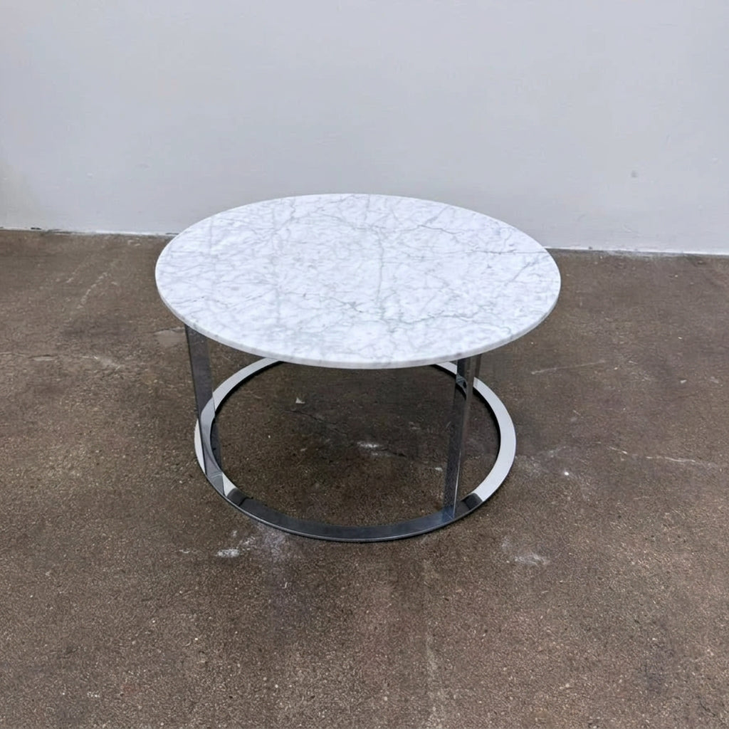 B&B Italia Mera Round Coffee Table with a white Carrara marble top and a dark metal circular base.