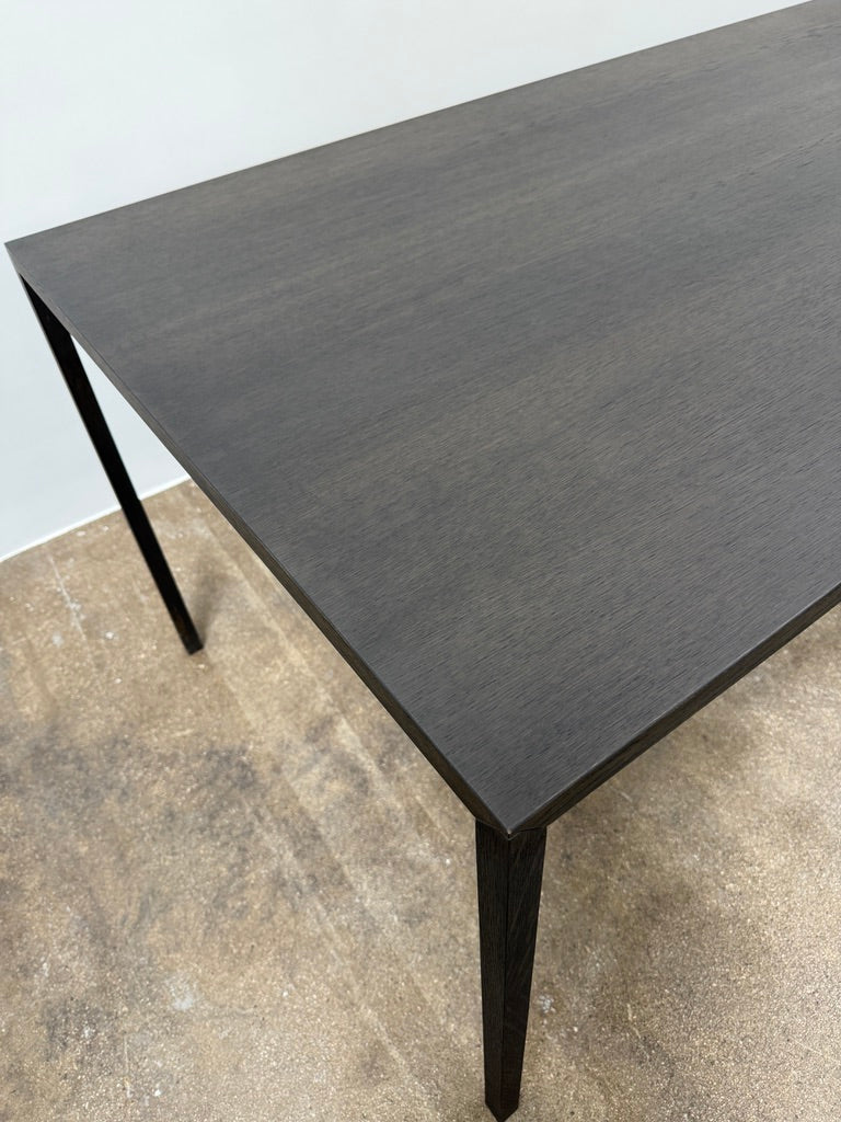 The Arco Slim Table by Arco is a minimalist rectangular table with a thin, flat surface and four slender legs, made from steel sandwich construction with a lightweight honeycomb core, shown against a plain white background.