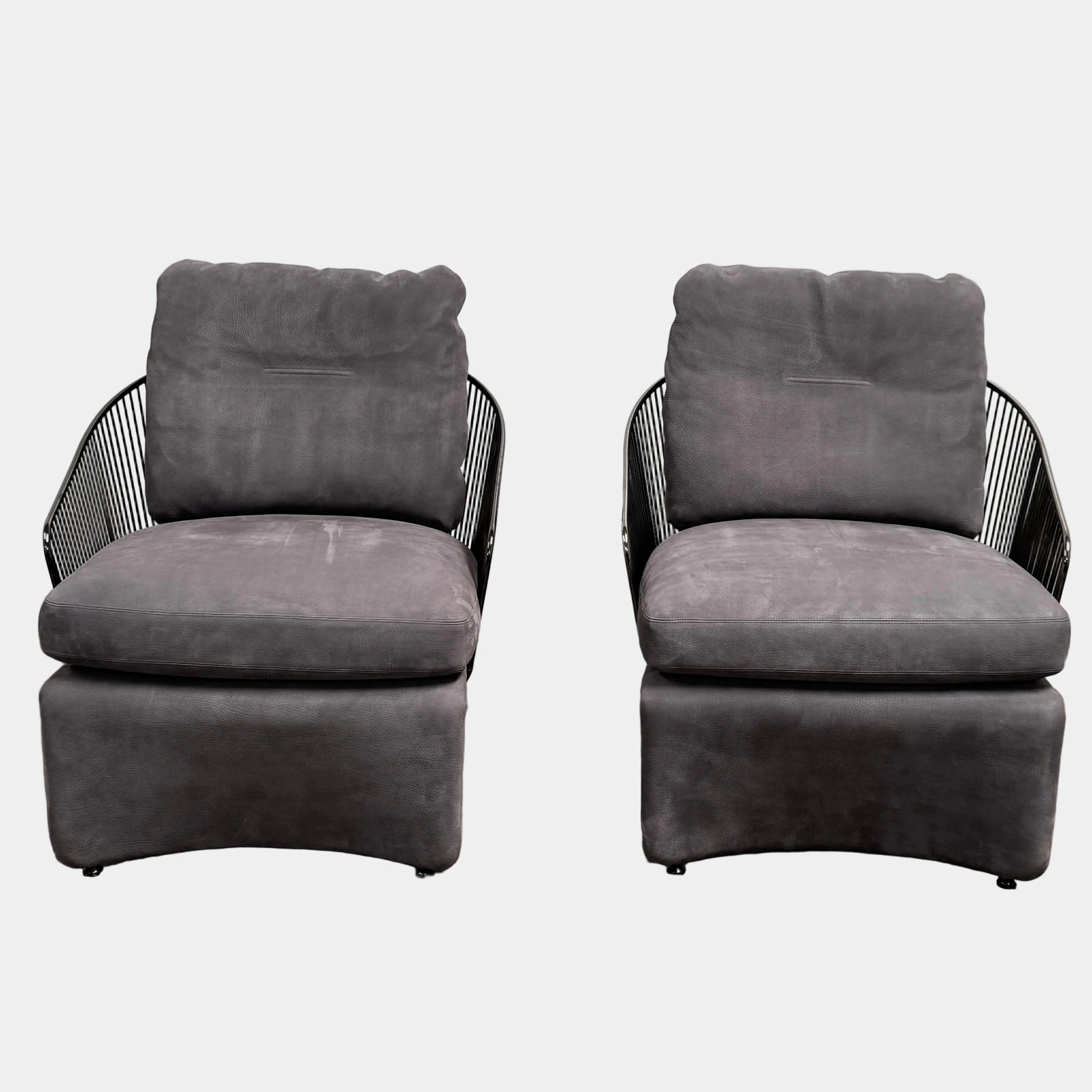 A set of two Minotti Colette Lounge Chairs by Minotti is displayed side by side against a plain white background. Each chair showcases luxurious gray nubuck leather upholstery and sleek black metal armrests, elegantly capturing the timeless mid-century silhouette characteristic of the iconic design.