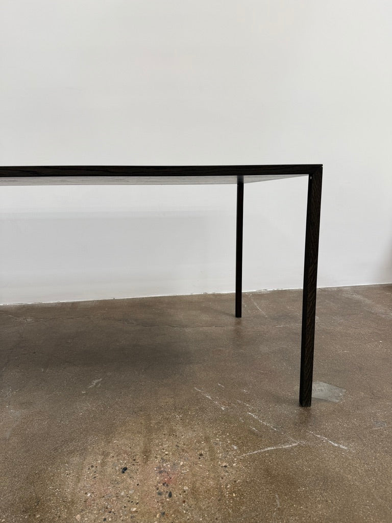 The Arco Slim Table by Arco is a minimalist rectangular table with a thin, flat surface and four slender legs, made from steel sandwich construction with a lightweight honeycomb core, shown against a plain white background.