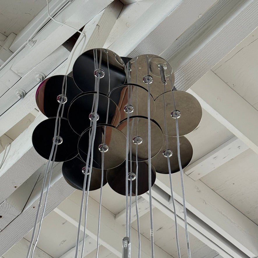 The Axo 12 Light Spillray Suspension Light by Modern Resale features cylindrical glass pendants and hangs from a high ceiling with exposed beams and fluorescent lighting.