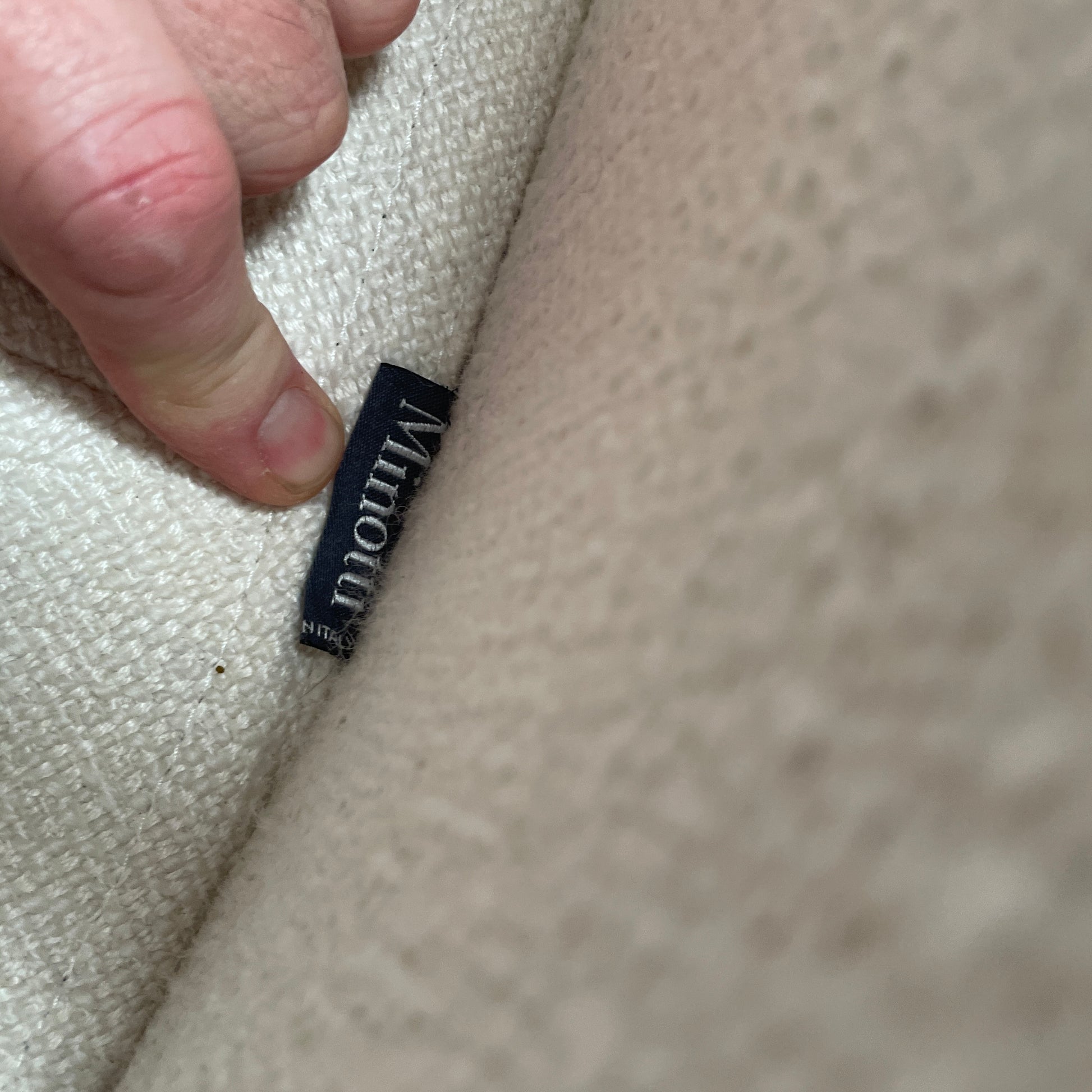 A Minotti Jacques Curved Sofa in white, featuring a contemporary design with curved lines and accompanied by two matching pillows, stands against a neutral background.