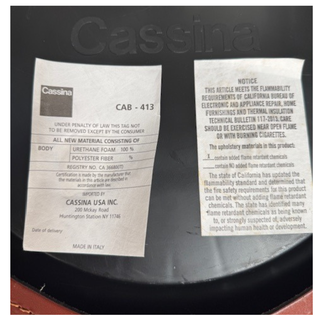 A red leather armchair, the Cassina Cab 413, drawing inspiration from the iconic Cab Chair with clean lines and a minimalist design, set against a plain grey background.