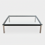 Cassina LC10 Low Glass Table featuring a low, square glass top, black frame, and four tubular metal legs in a mid-century modern style.