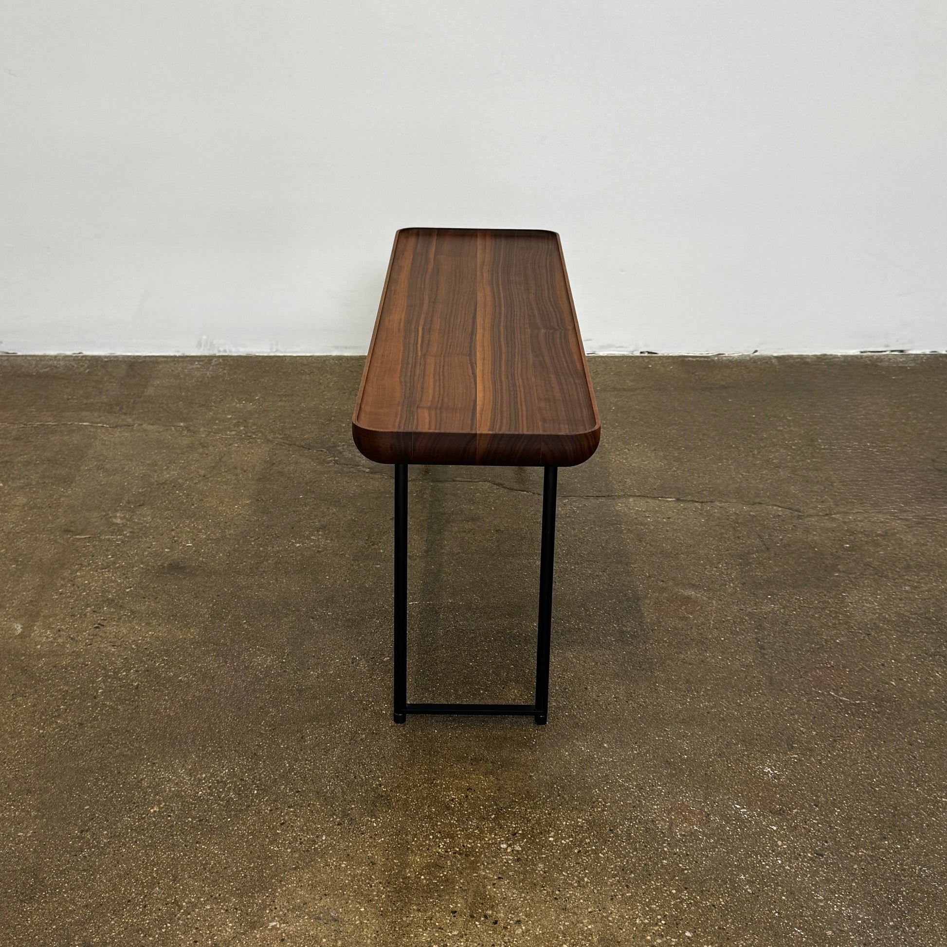 The Cassina Torei Occasional Table in Walnut by Cassina features rounded edges and sleek black metal legs, shown on a plain white background.