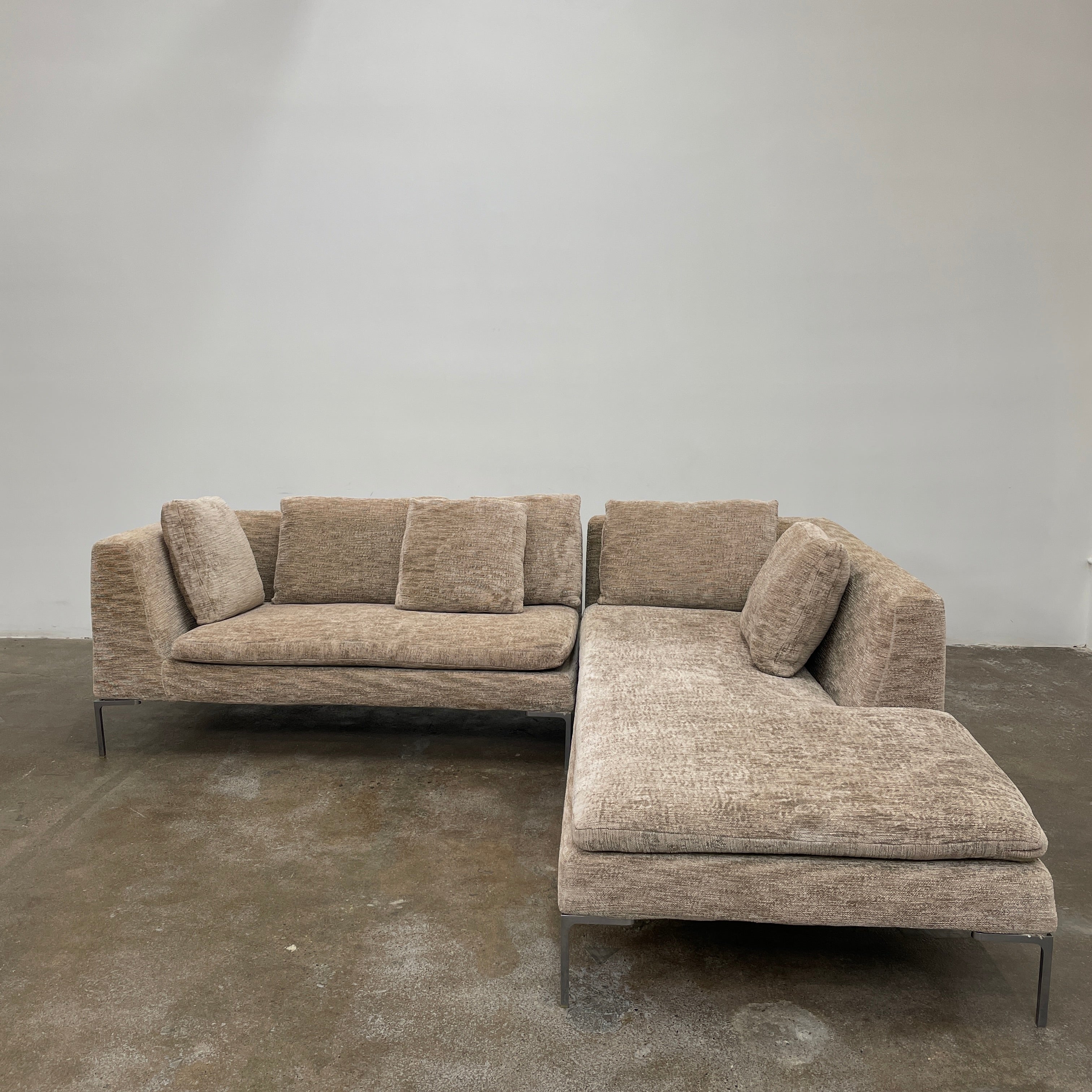 Introducing the B&B Italia Charles Sectional by Modern Resale: This beige L-shaped sectional sofa features textured fabric and stylish thin black metal legs. Set against a plain white background, it embodies modern elegance and timeless design.
