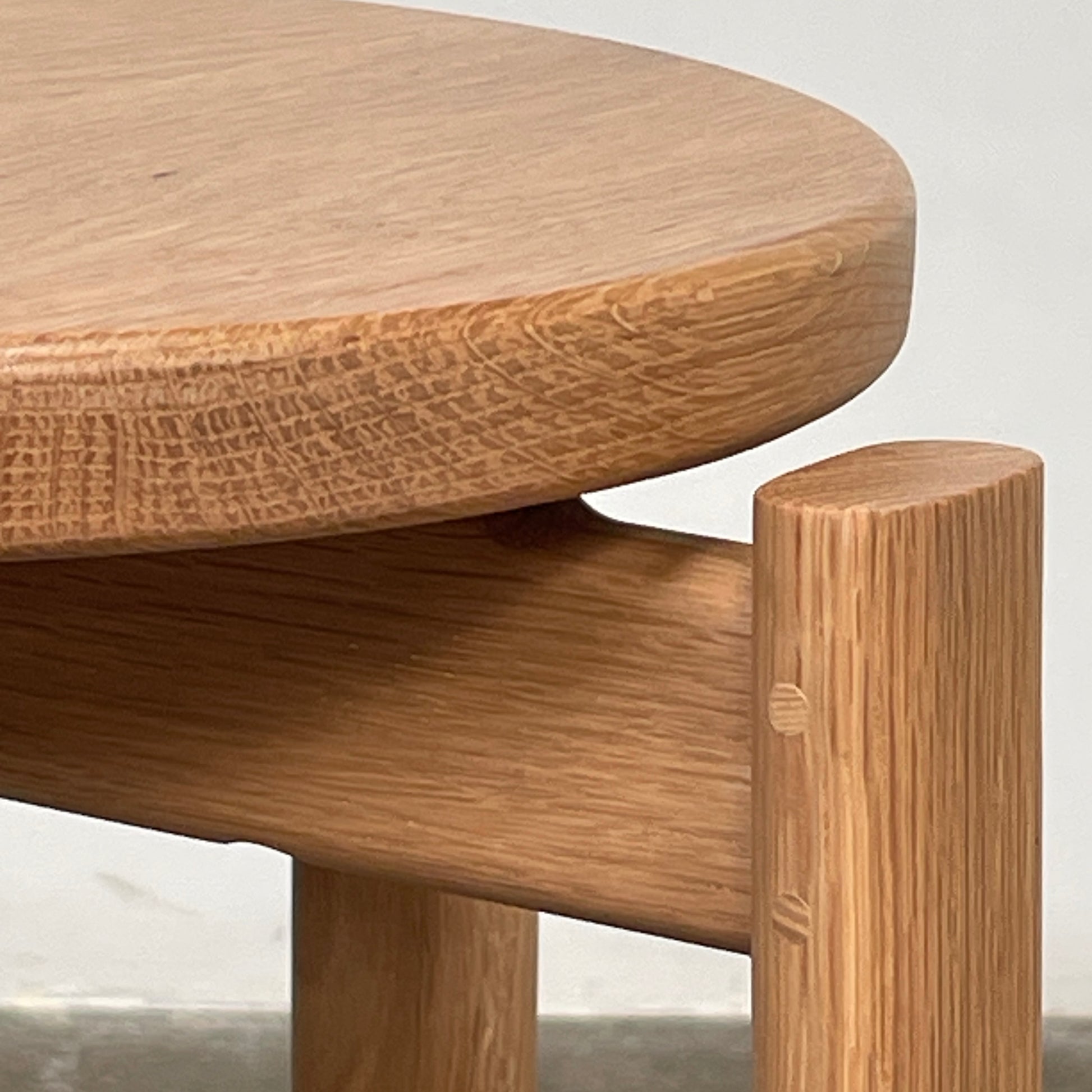 Audo Passage Bar Stools by Audo—two solid oak stools with round seats, three legs, and a black circular metal footrest—highlight Danish craftsmanship, shown against a plain white background.