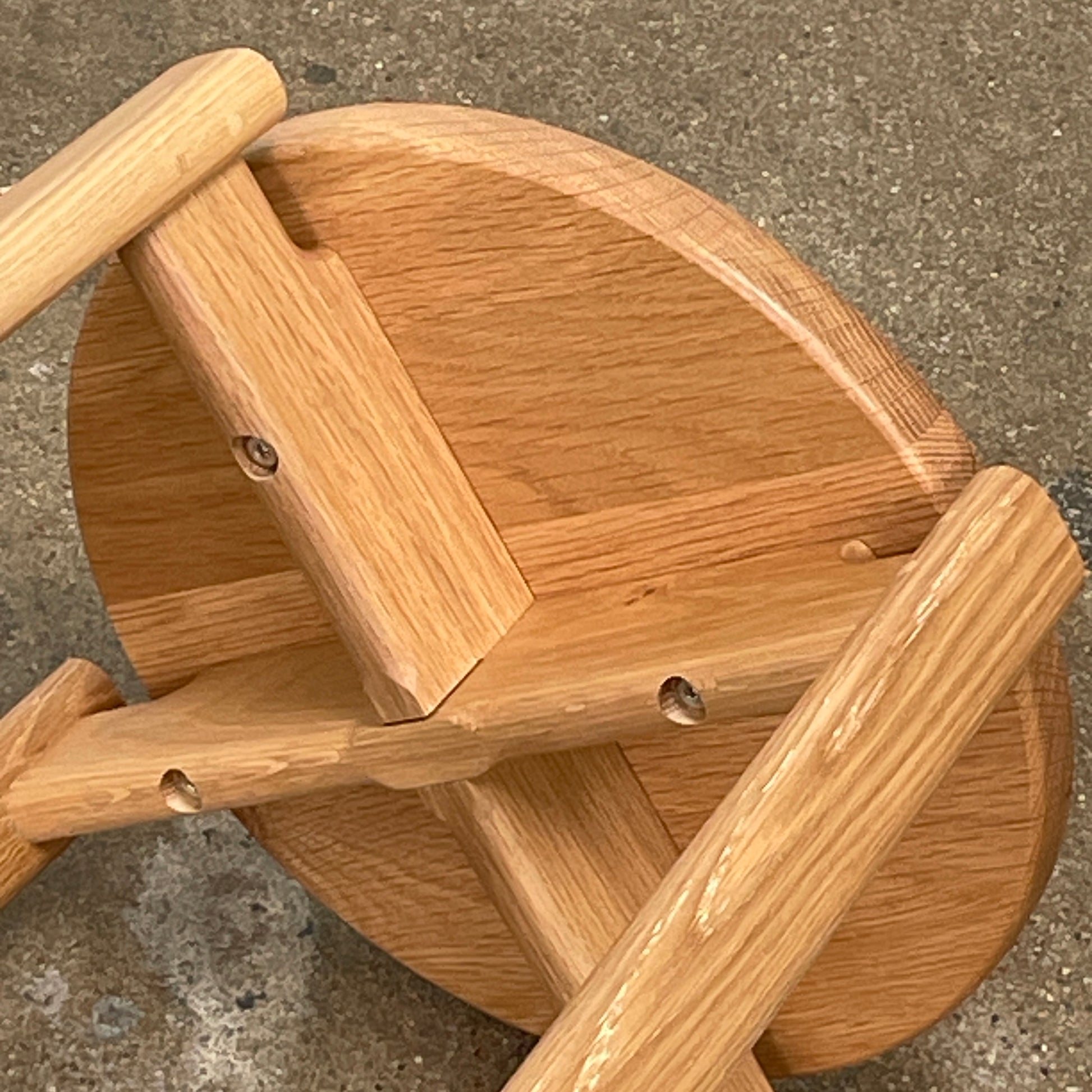 Audo Passage Bar Stools by Audo—two solid oak stools with round seats, three legs, and a black circular metal footrest—highlight Danish craftsmanship, shown against a plain white background.