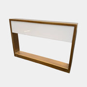 The Arterior Aura LED Table Lamp in Antique Brass by Arterior is paired with a modern console table featuring a gold rectangular frame and single white drawer, set against a plain white background.
