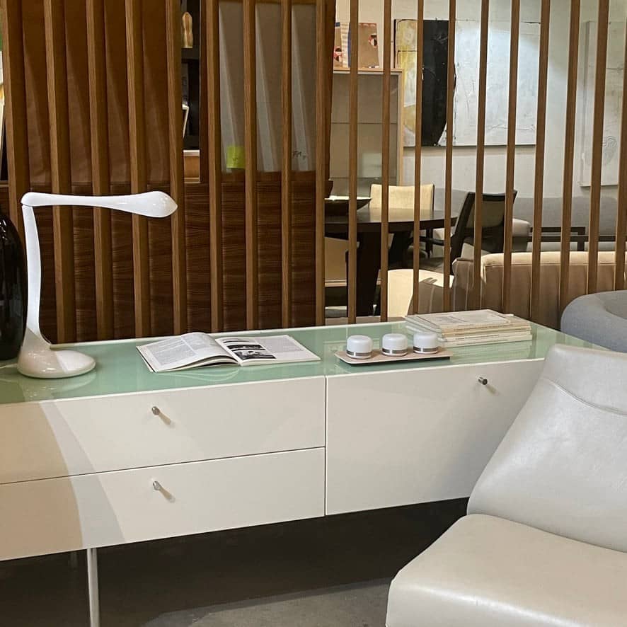 The Cassina 255-256 Flat Sideboard in glossy white lacquer features two left drawers, a spacious right compartment, and four metal legs, all by Cassina, shown against a plain background.