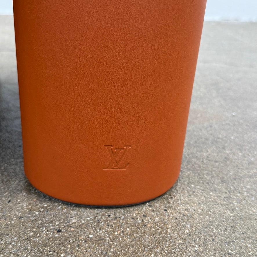 The Louis Vuitton Dolls Fur by Raw Edges is a modern chair with a curved white fluffy leather and fur seat, two short cylindrical brown legs, and a matching brown base, designed by Louis Vuitton and set against a plain background.