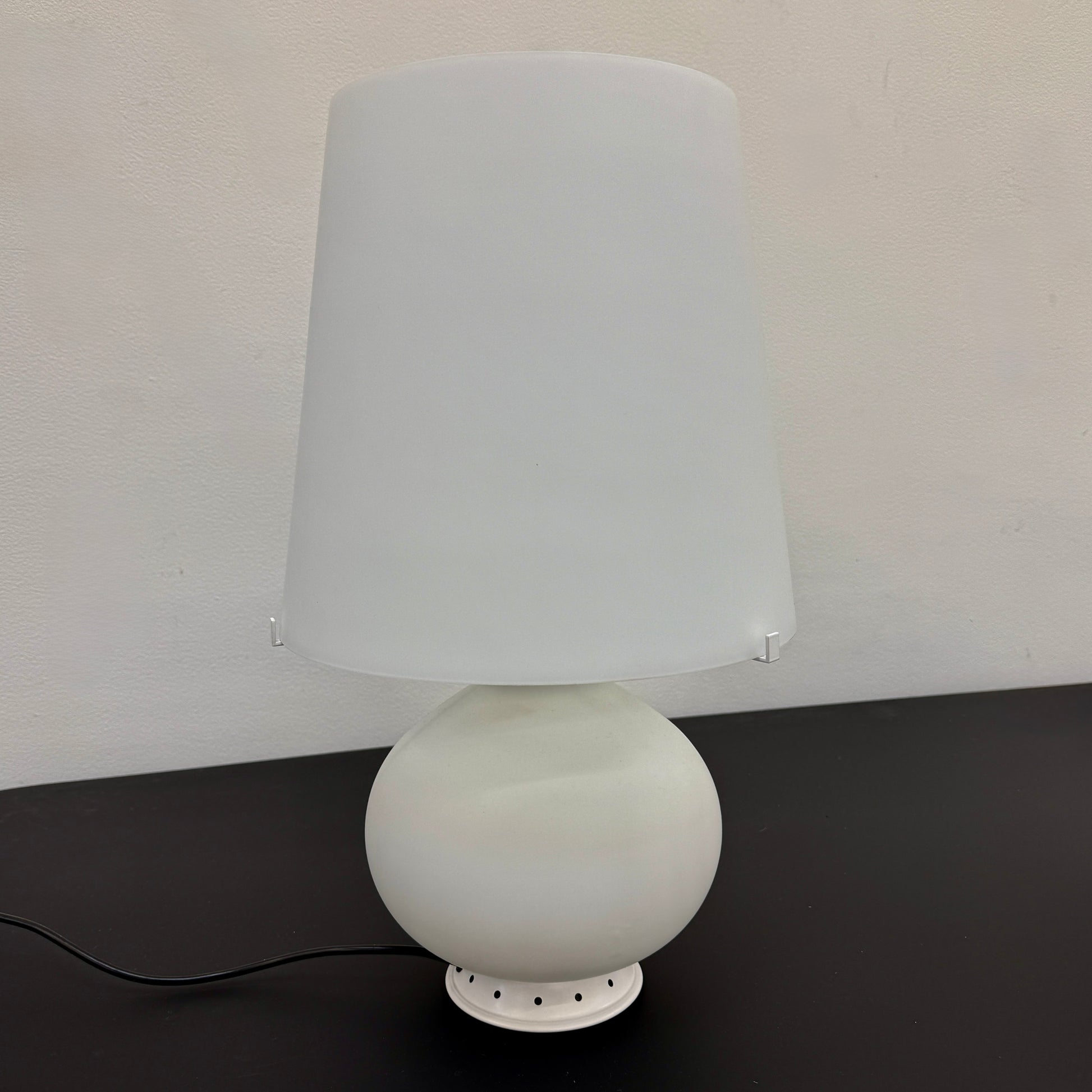 The Fontana Arte Table Lamp - Medium by Fontana Arte features a modernist design with a round base and wide, tapered lampshade, displayed against a plain light background.