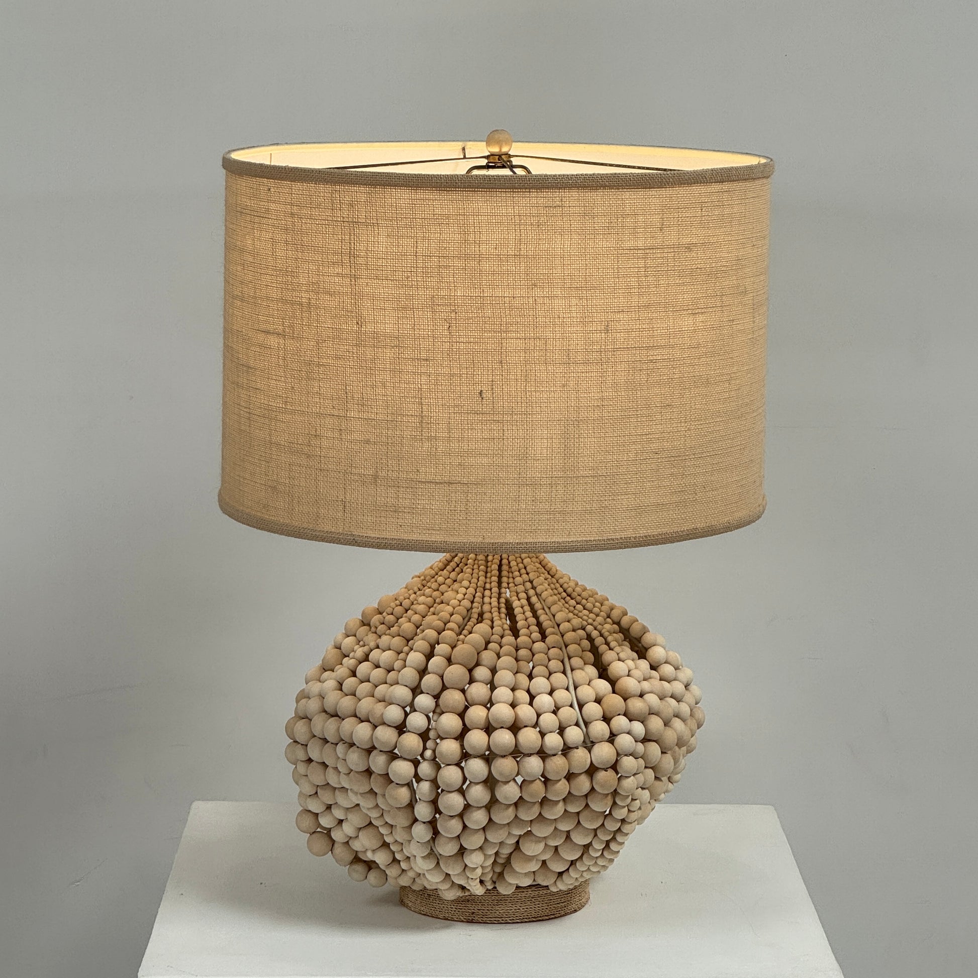 The Palecek Point Dume Table Lamp by Palecek features a clustered wooden bead base and a cylindrical beige fabric shade, offering relaxed coastal elegance for your space.
