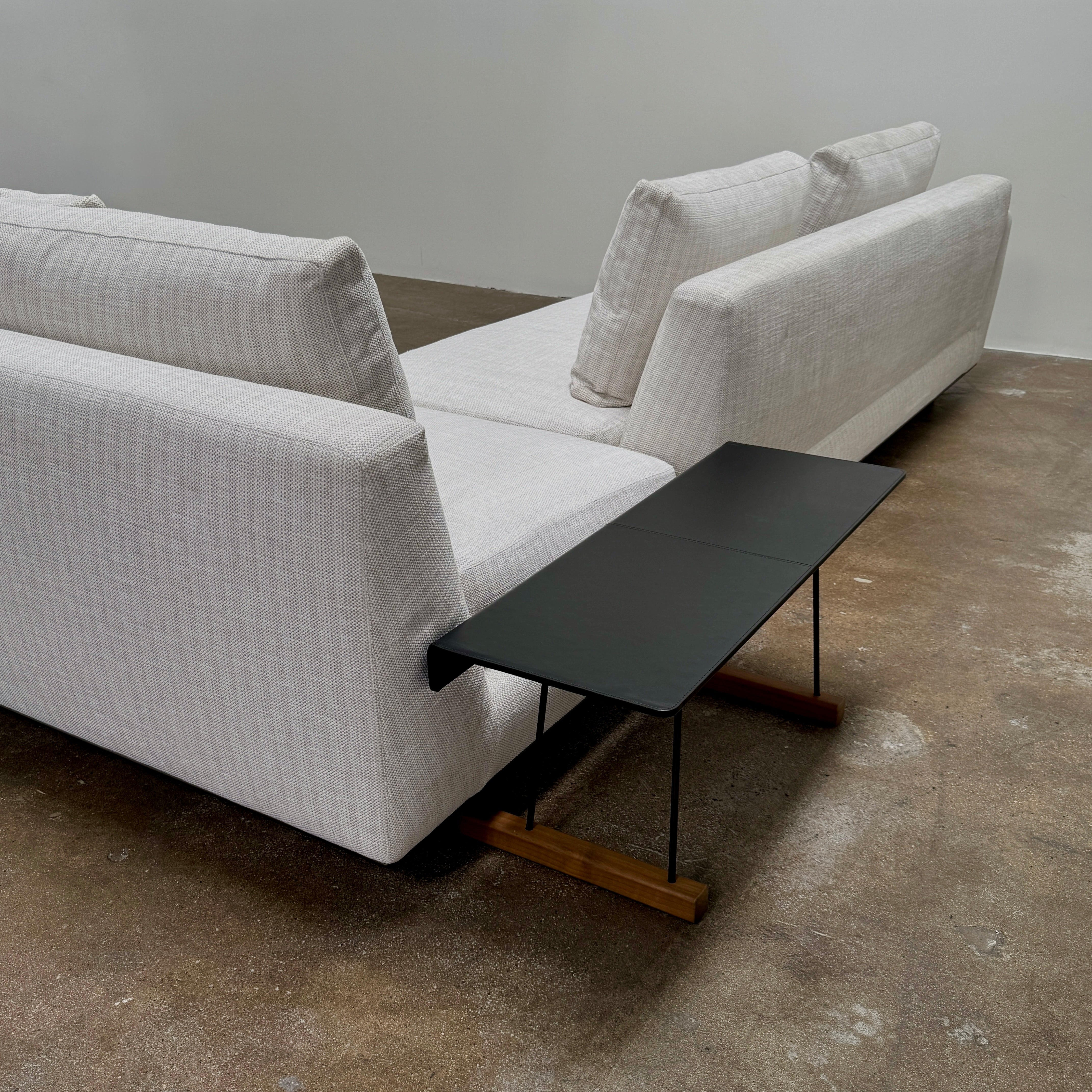 The Walter Knoll Tama Living 3 Piece Modular Sofa by Walter Knoll features an L-shaped design in light gray luxury fabric, matching cushions, and a built-in wooden side table on the right.