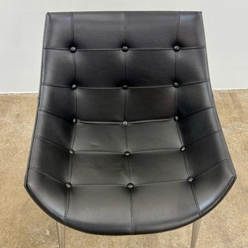The Cassina Passion Side Chair by Cassina is a modern black upholstered chair with a curved backrest, button detailing, and four sleek metal legs inspired by the Passion design.