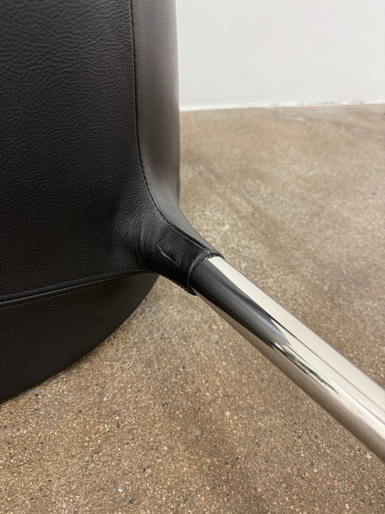 The Cassina Passion Side Chair by Cassina is a modern black upholstered chair with a curved backrest, button detailing, and four sleek metal legs inspired by the Passion design.