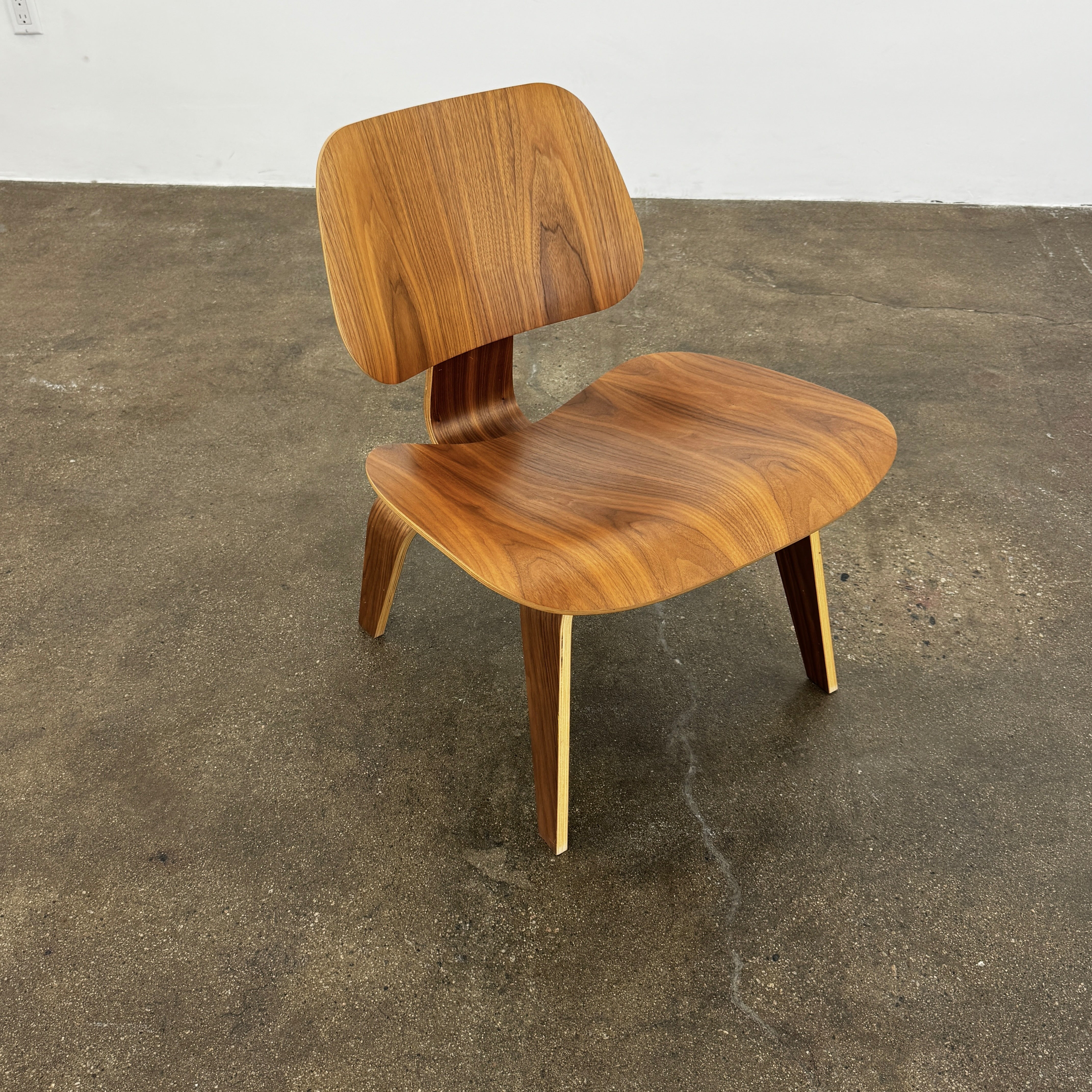 The MillerKnoll Eames Molded Plywood Lounge Chair Wood Base (LCW), featuring a curved seat, angled backrest, and splayed legs, is displayed against a plain light background.