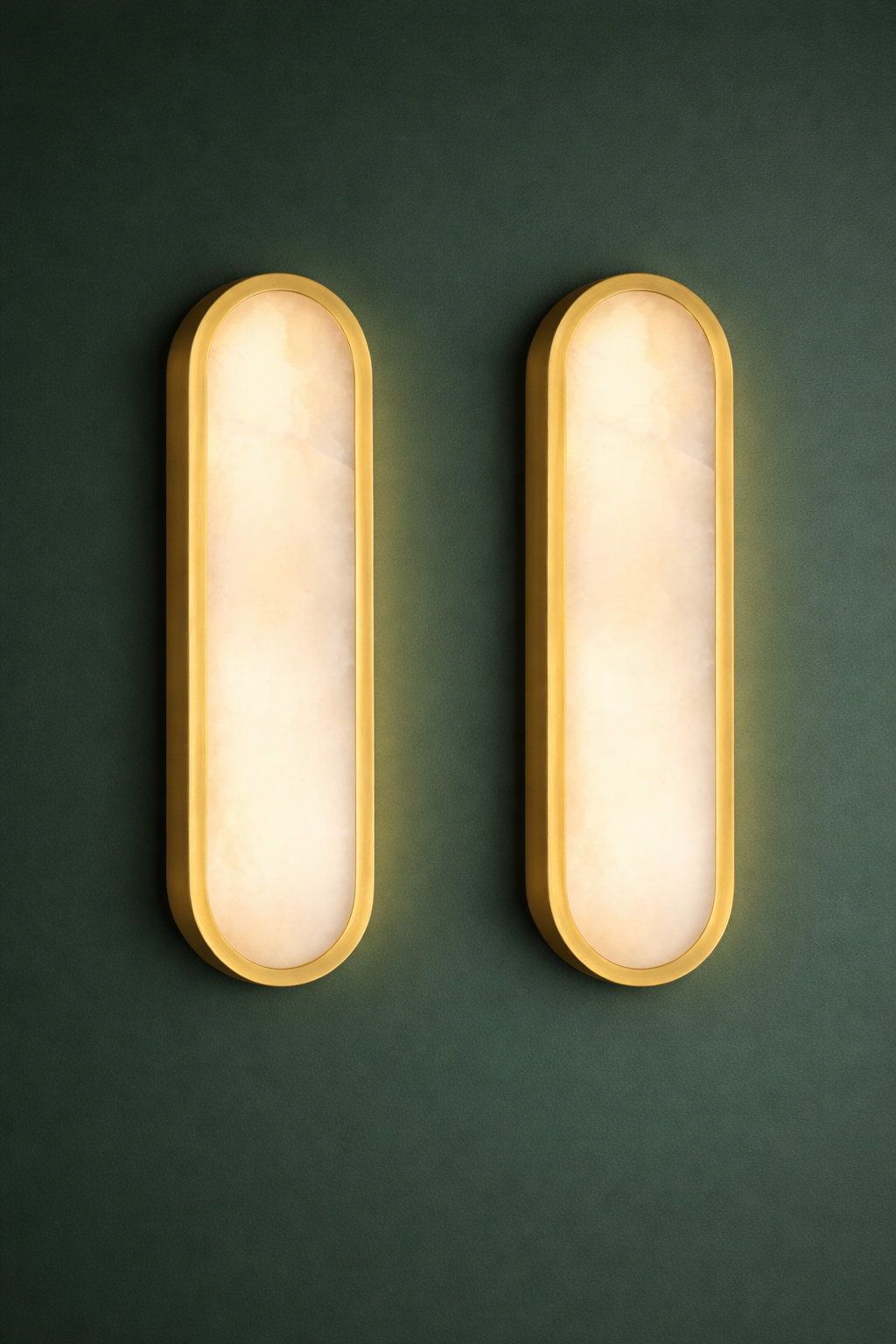 Two Hudson Valley Lighting Manhasset LED Wall Sconces (set of 2) with gold metal frames and frosted alabaster diffusers are mounted on a plain white wall.