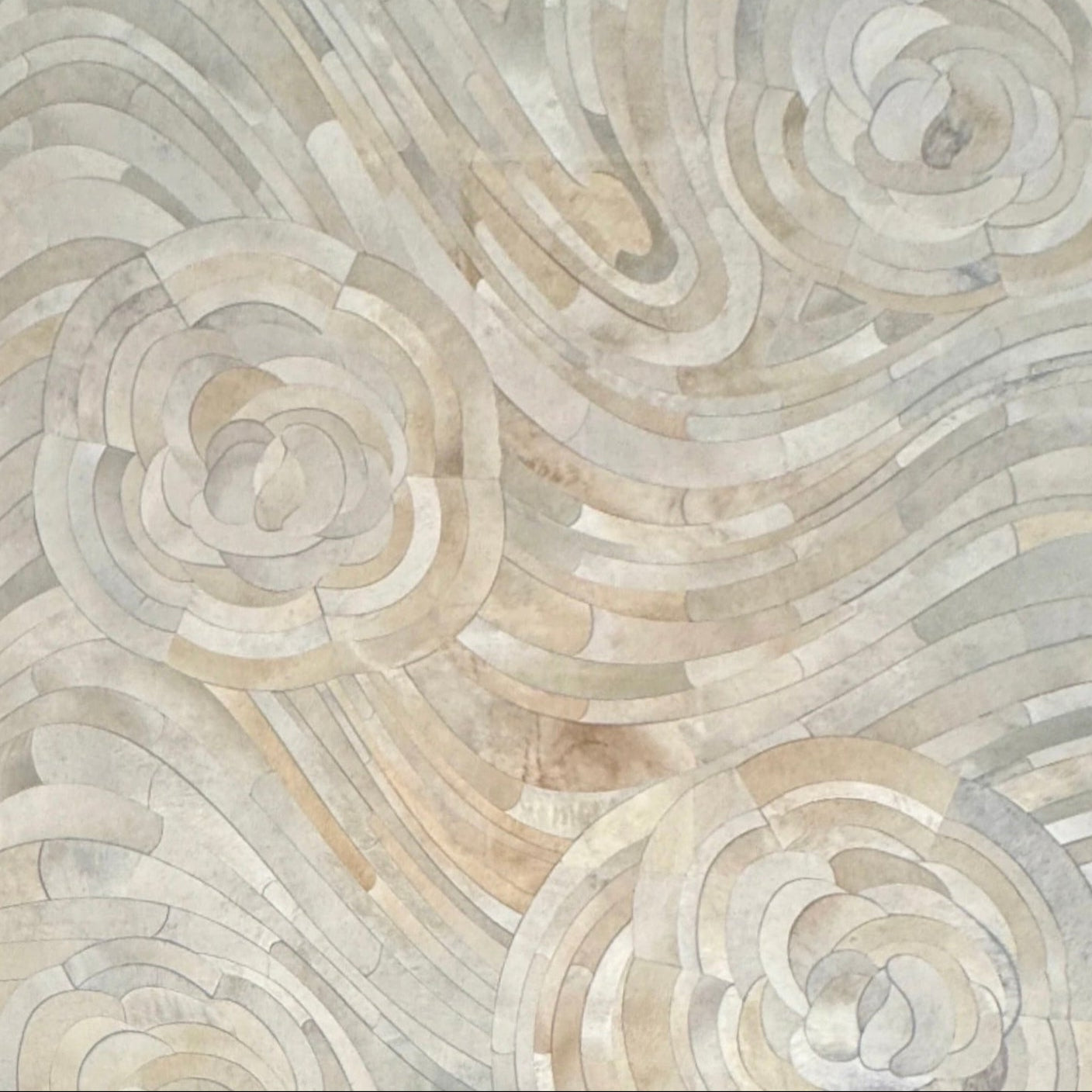 The Kyle Bunting Hide Rug - Drift by Kyle Bunting features a rectangular form with wavy, swirling abstract patterns in beige, cream, and light gray, accented by circular, flower-like designs that highlight exquisite craftsmanship.