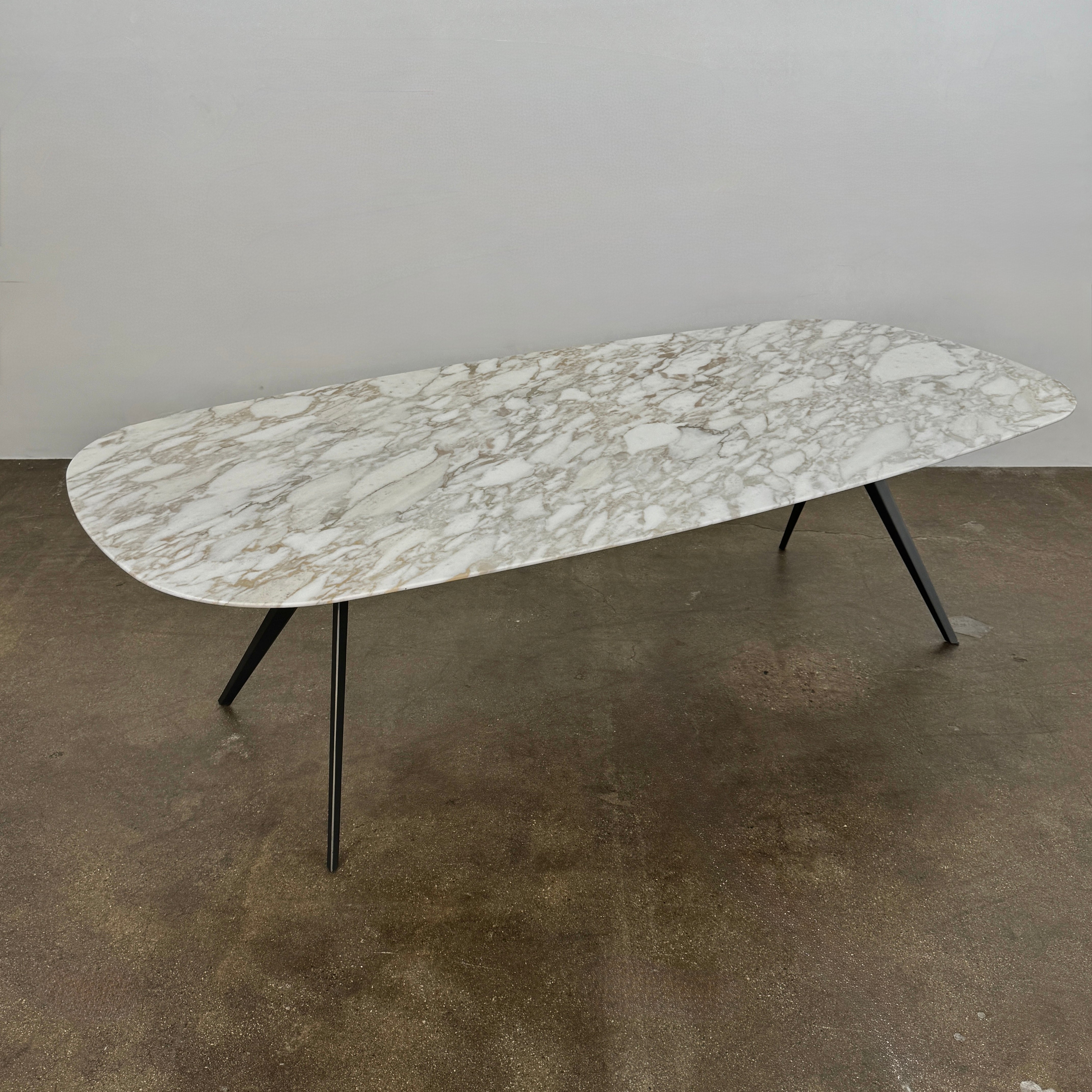 The Flexform Zefiro Dining Table by Flexform features a rectangular Calacatta Gold marble top with rounded edges and four black angled legs, shown on a plain white background.