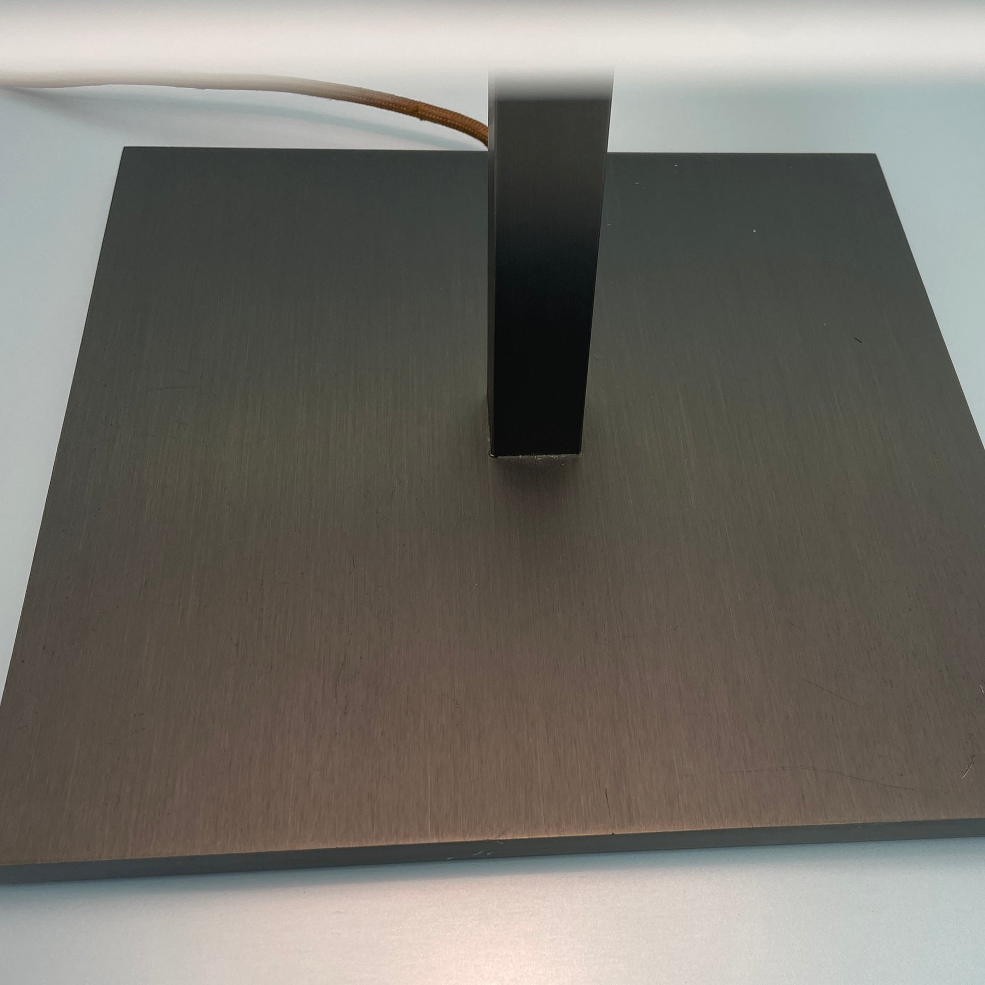 Introducing the Flos Metropolitan Table Light by Flos: a chic table lamp with a rectangular shade adorned with a diamond pattern, gracefully positioned on a square base.