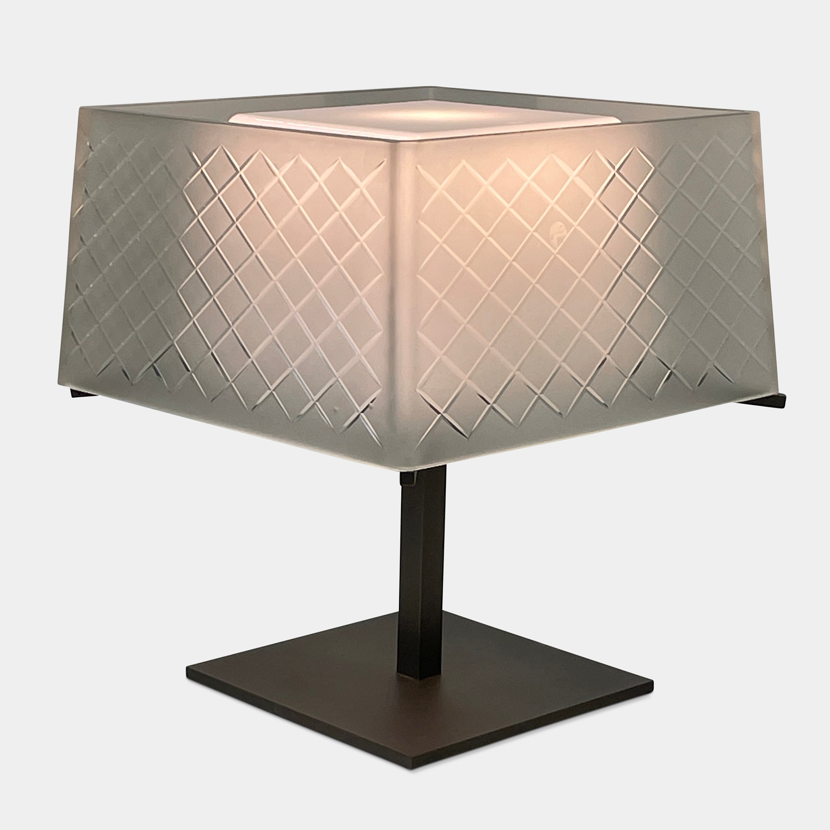 Introducing the Flos Metropolitan Table Light by Flos: a chic table lamp with a rectangular shade adorned with a diamond pattern, gracefully positioned on a square base.