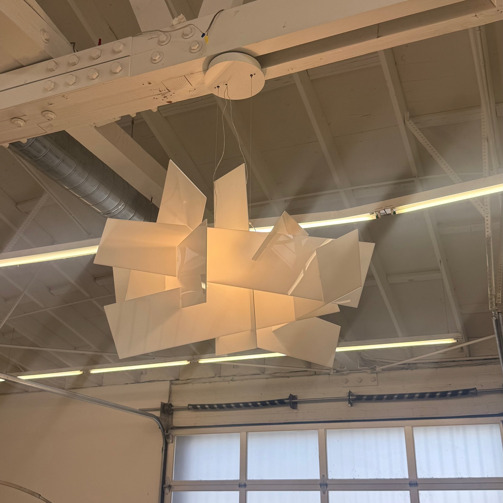 The Foscarini Big Bang LED Pendant, by Foscarini, features sculptural overlapping rectangular panels that emit a warm glow—ideal statement lighting for contemporary spaces.