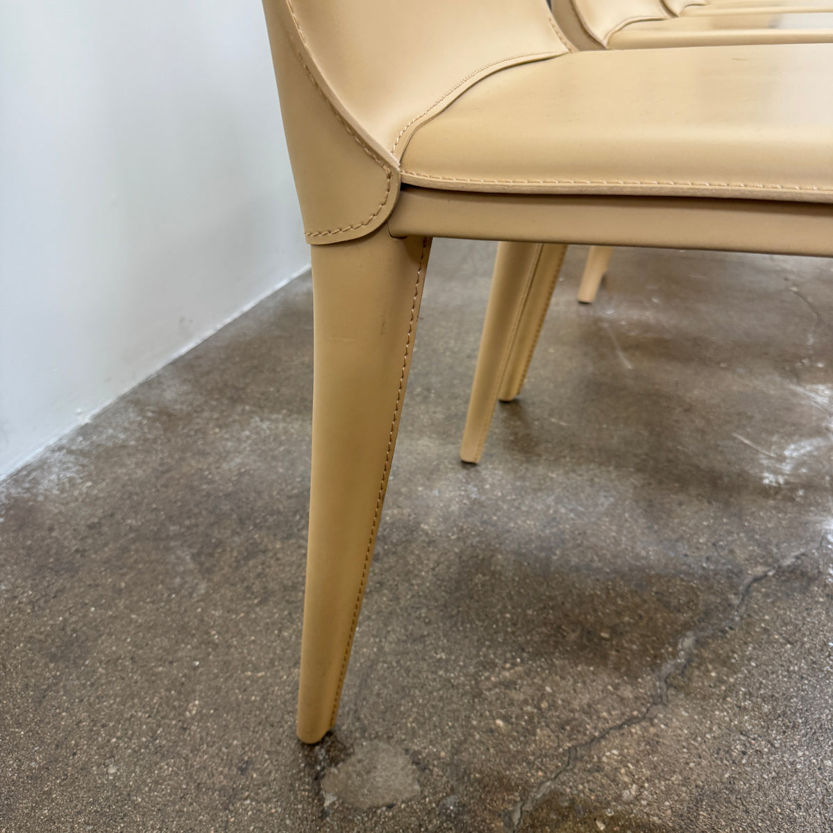 Eight light-tan Frag Bottega leather dining chairs arranged in two rows.