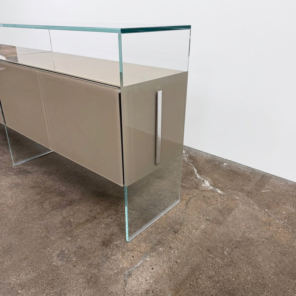 A long Gallotti & Radice Air Console Table featuring a clear glass frame and four opaque taupe storage cabinets.