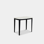 The Poliform Henry Marble Side Table, by Poliform, showcases an elegant small oval design with a luxurious Carrara marble top. It stands gracefully on four black Elm legs against a minimalist white backdrop.