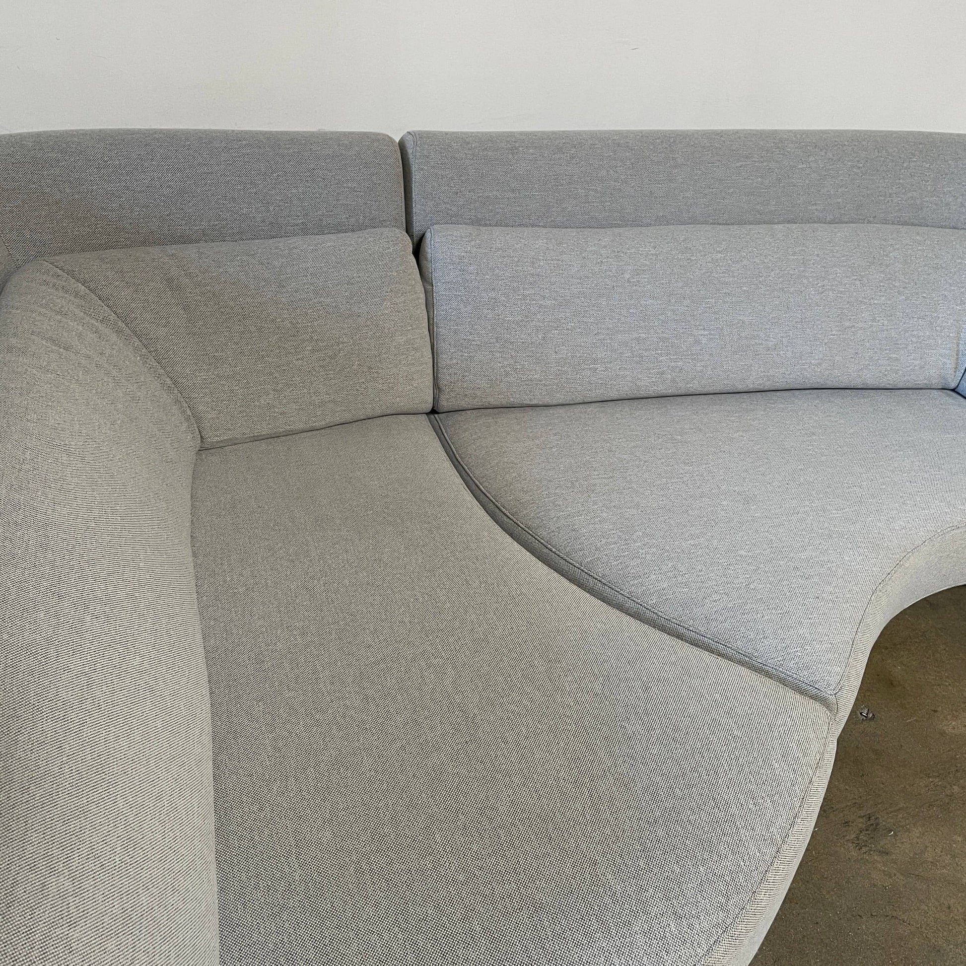 Modern curved Ligne Roset Yang Sectional sofa in durable wool fabric, isolated on a white background.