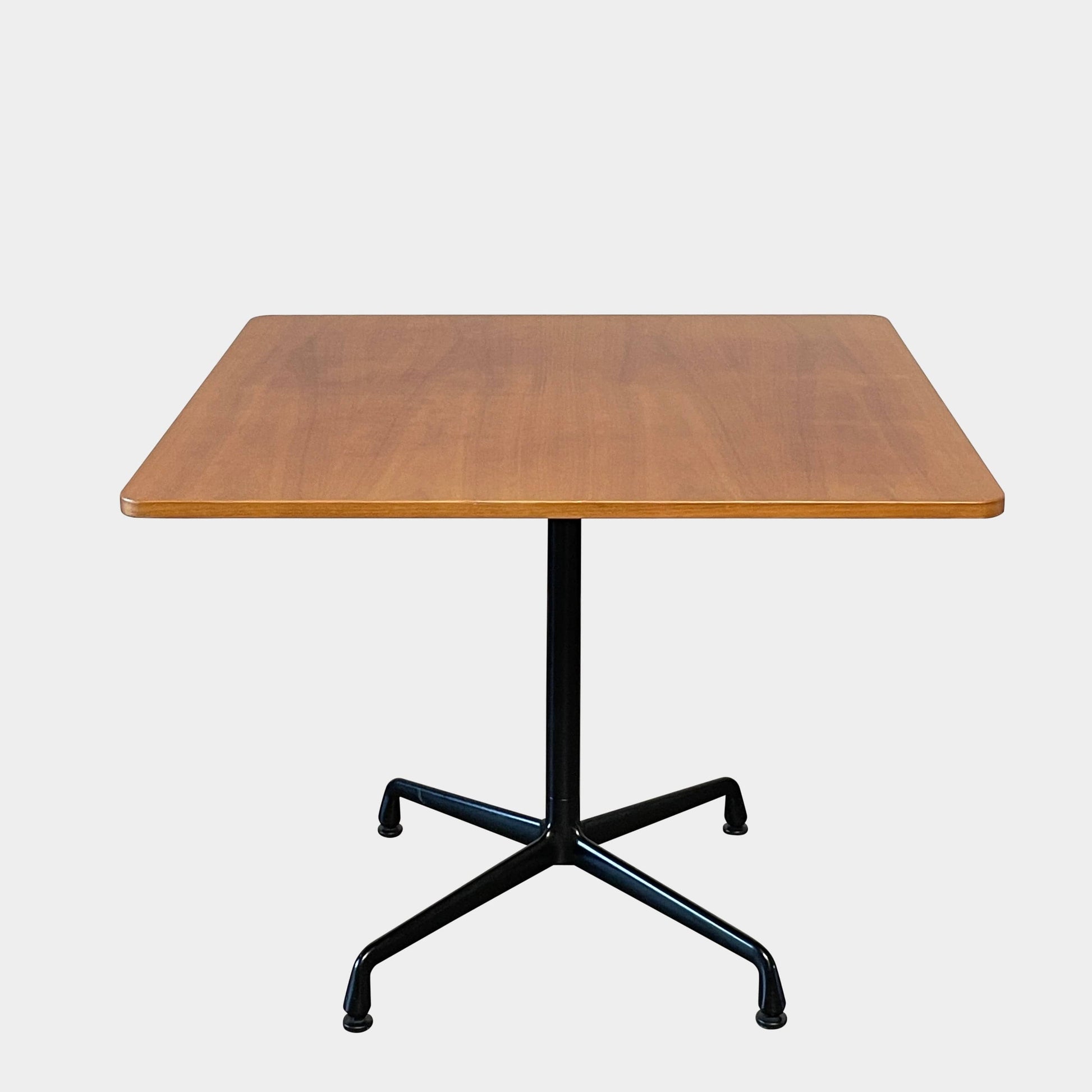 A Herman Miller Square Table with a black base and wooden top by Herman Miller.