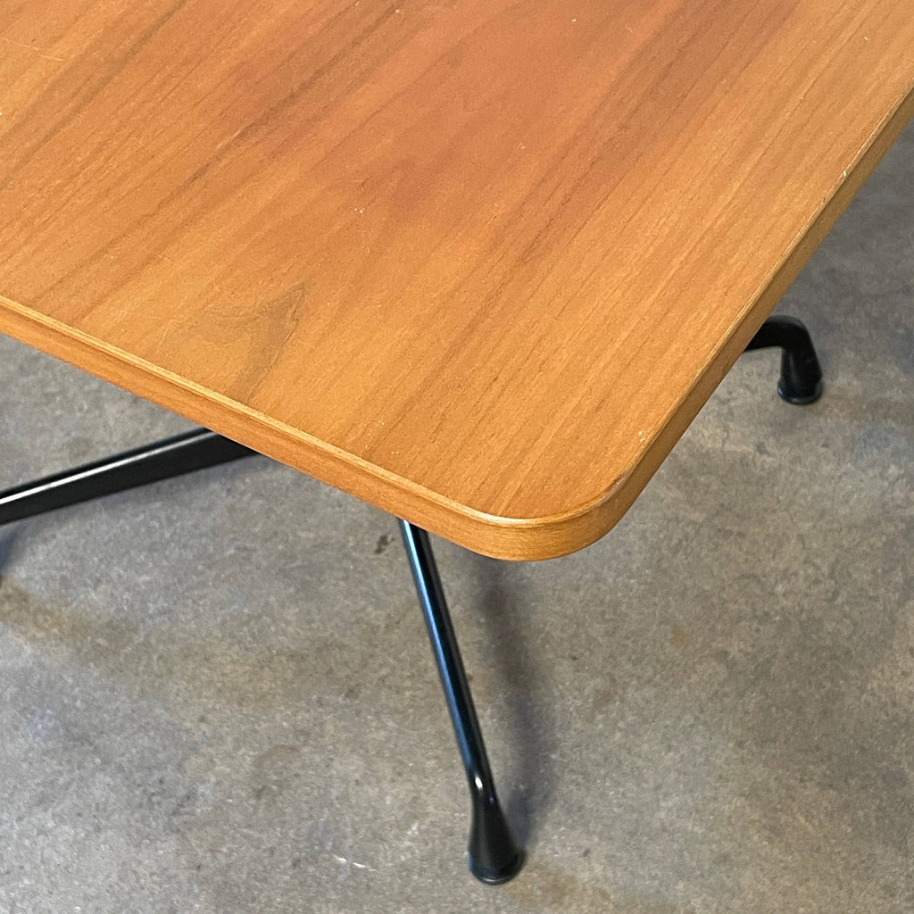 A Herman Miller Square Table with a black base and wooden top by Herman Miller.