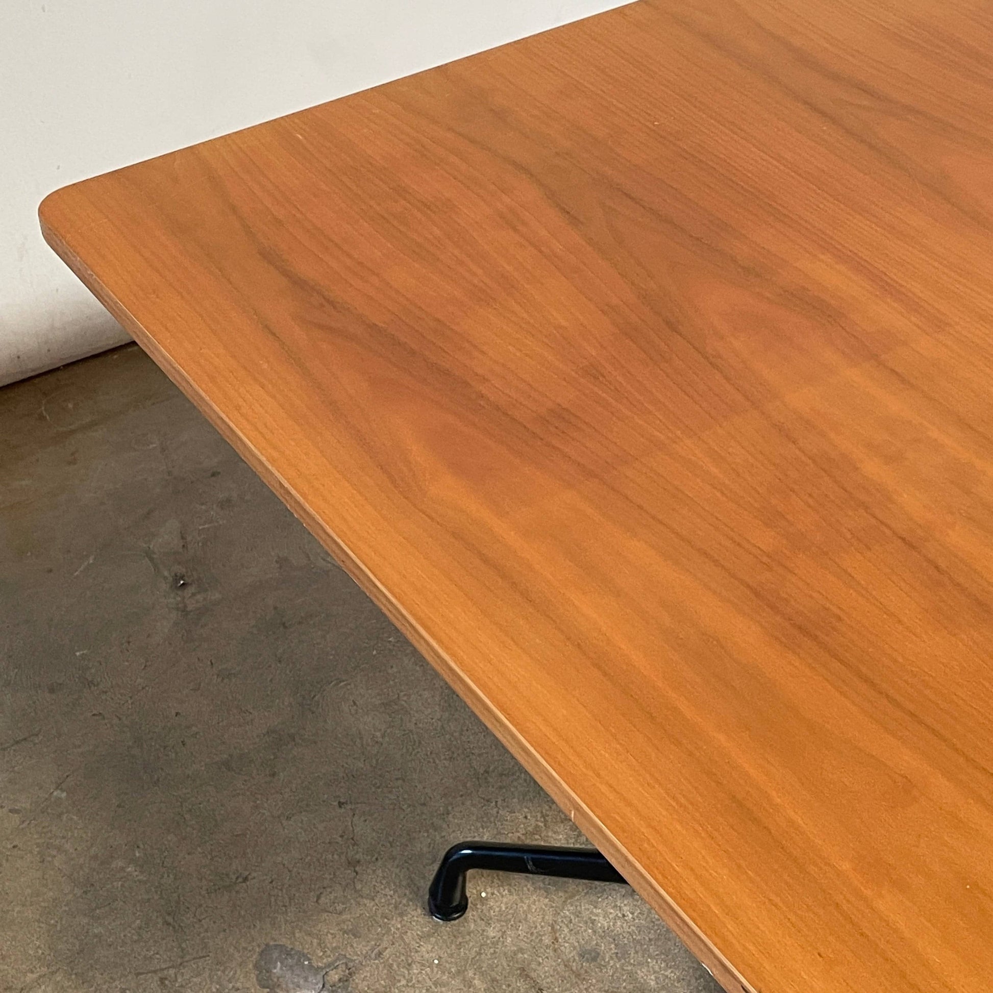 A Herman Miller Square Table with a black base and wooden top by Herman Miller.