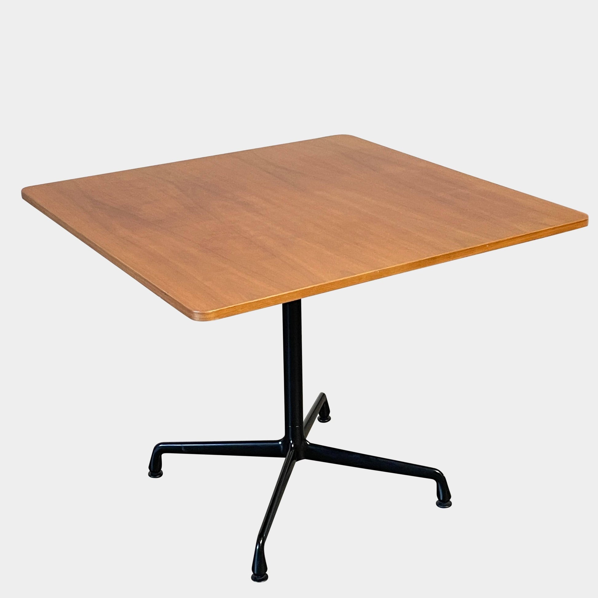 A Herman Miller Square Table with a black base and wooden top by Herman Miller.