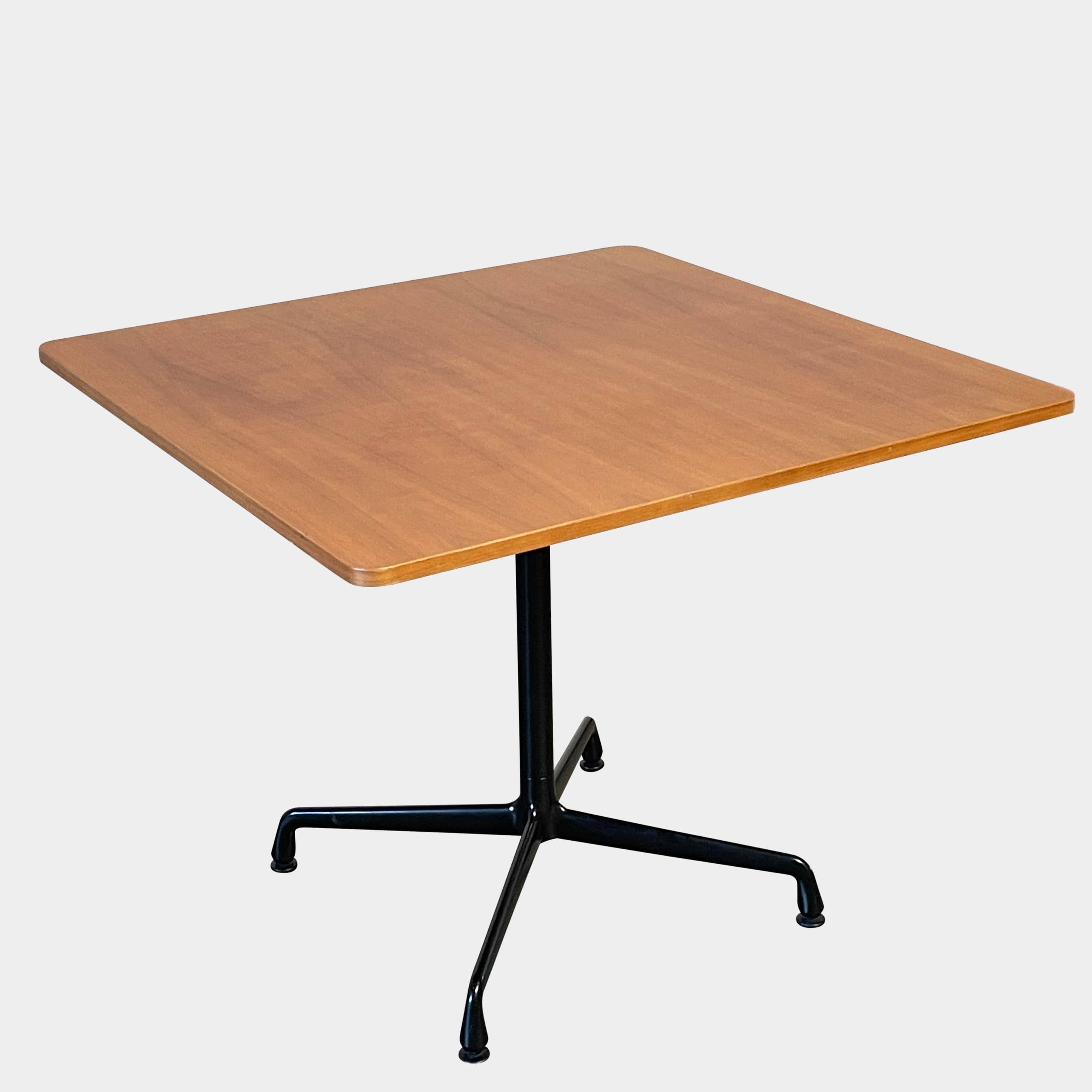 A Herman Miller Square Table with a black base and wooden top by Herman Miller.