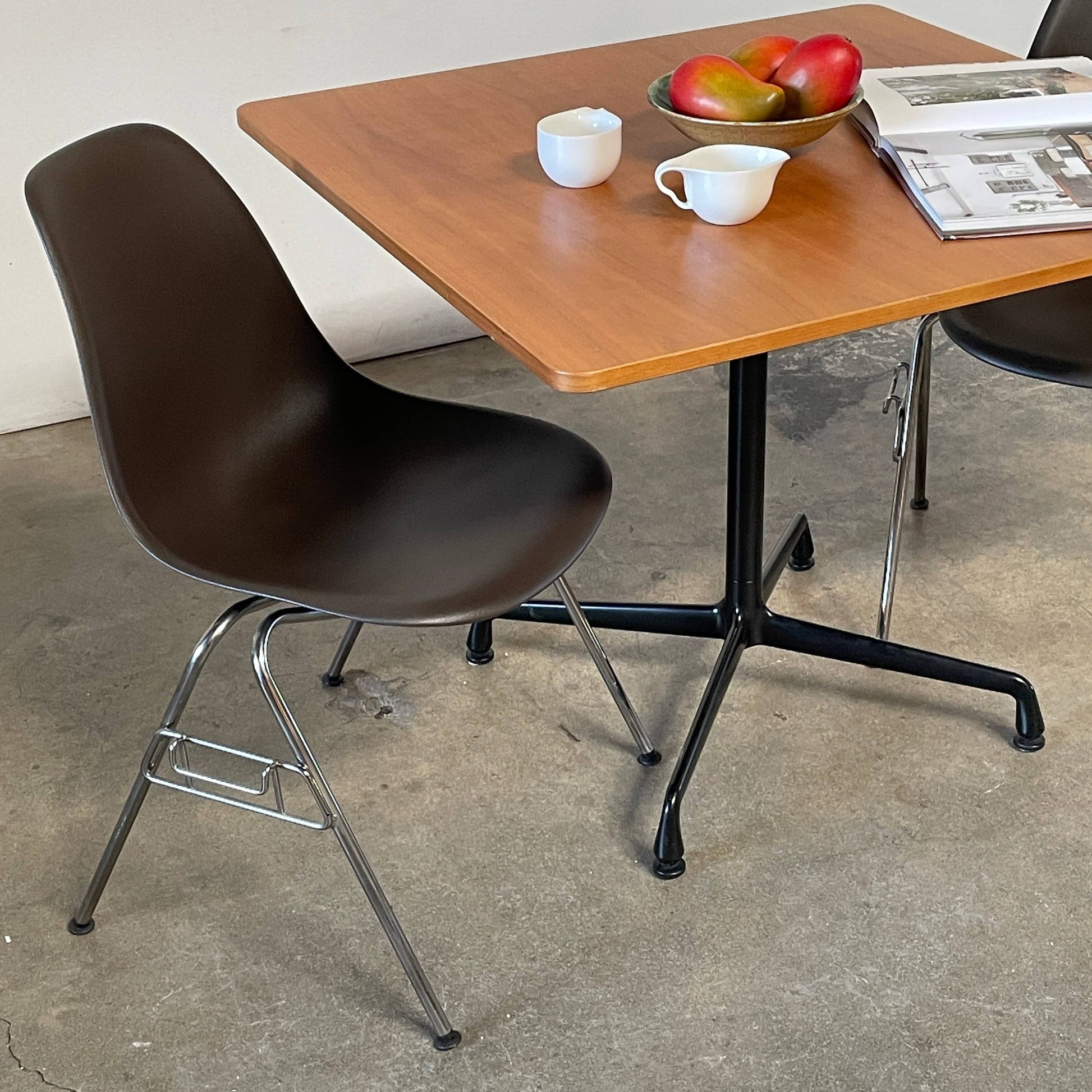 A Herman Miller Square Table with a black base and wooden top by Herman Miller.