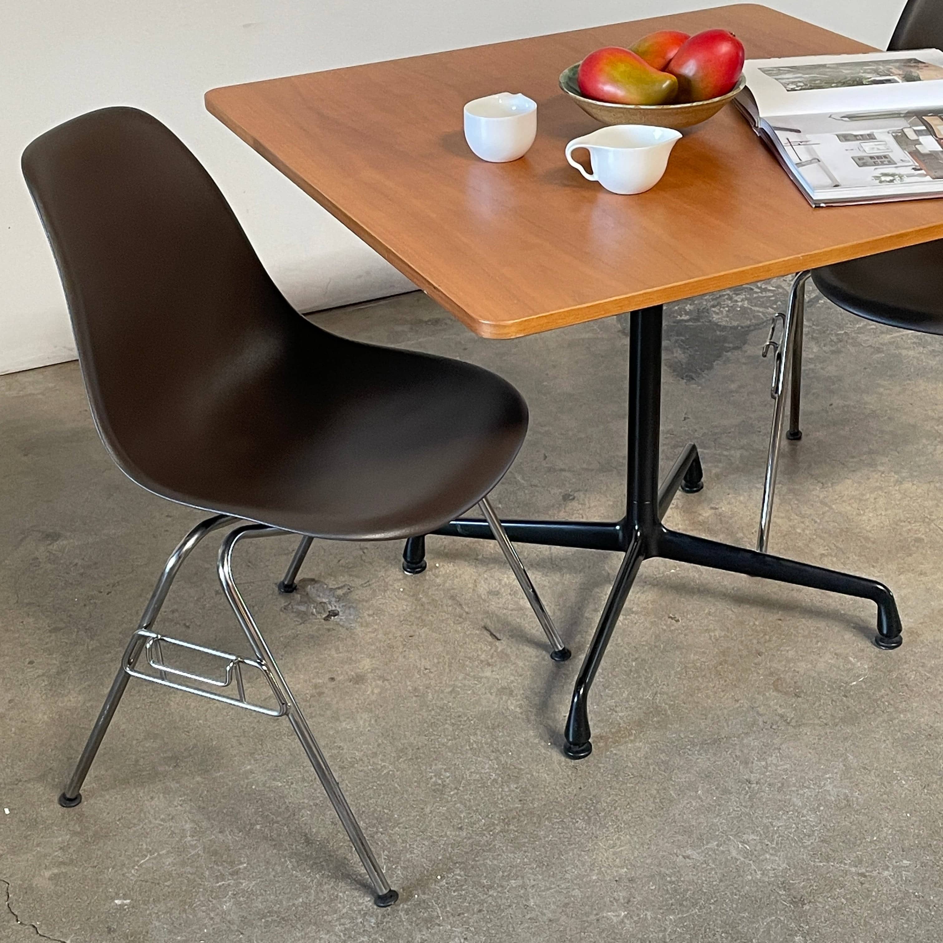 A Herman Miller Square Table with a black base and wooden top by Herman Miller.