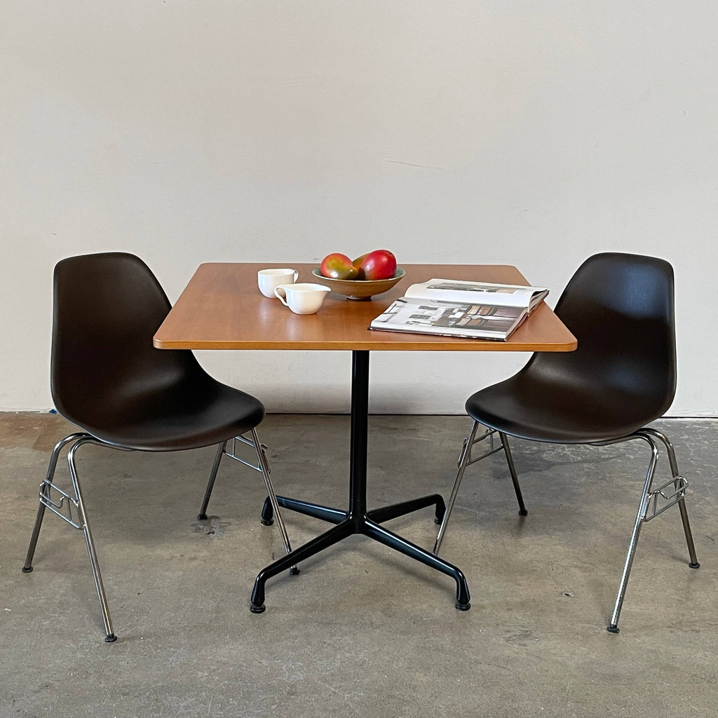 A Herman Miller Square Table with a black base and wooden top by Herman Miller.