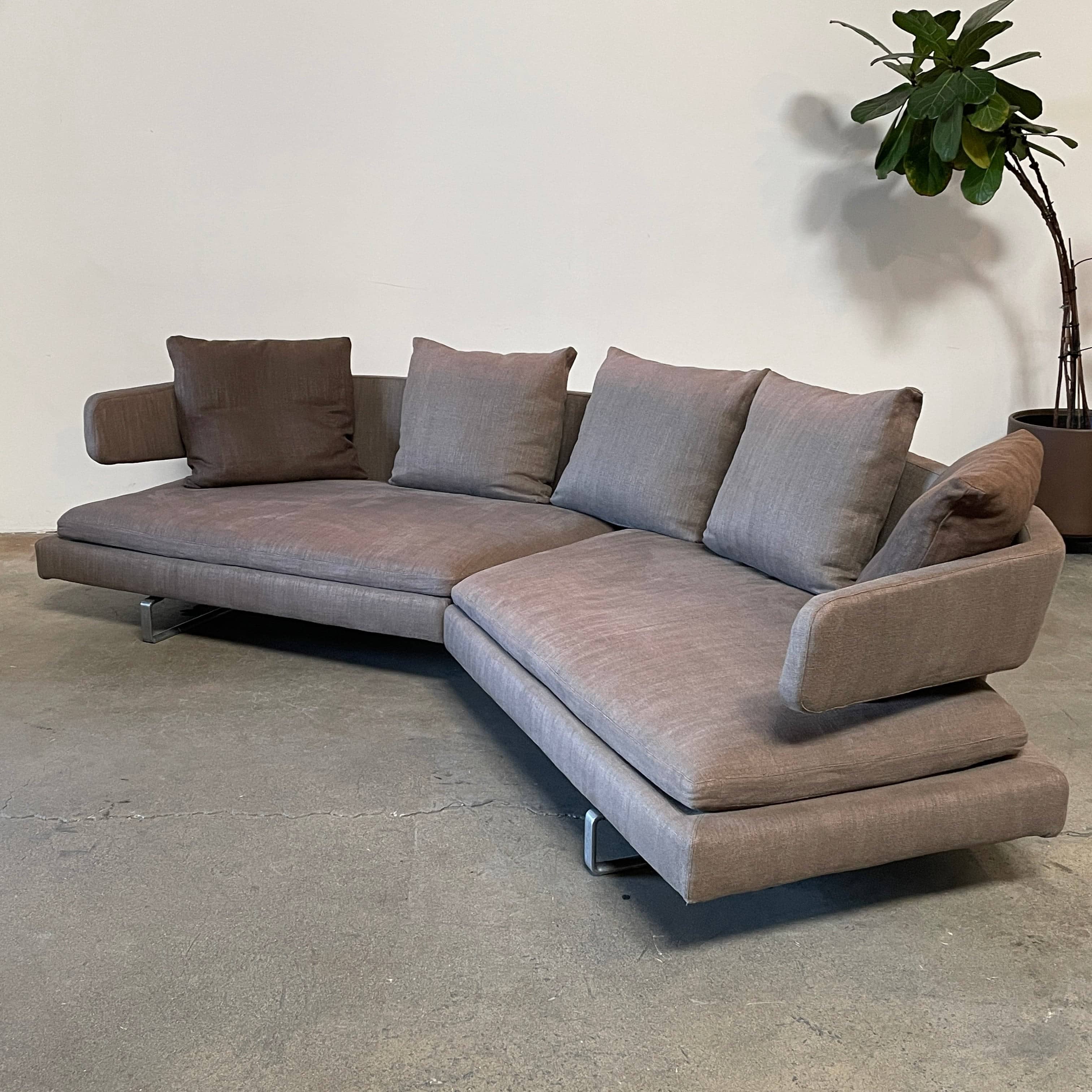 Modern upholstered l-shaped sectional B&B Italia Arne Sofa designed by Antonio Citterio, with cushions on a white background.